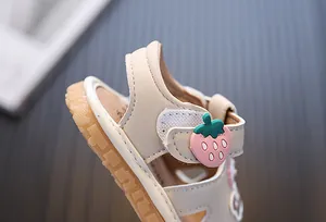 Dettaglio sandalo beige per neonato con decorazione a fragola e chiusura a strappo
