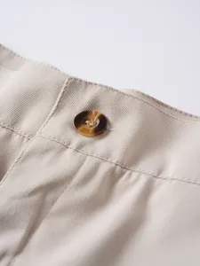 Nahaufnahme vom beigen Herren-Shorts-Bund mit hochwertigem braunem Schildpatt-Knopf