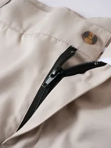 Detailansicht des hochwertigen Reißverschlusses und Knopfverschlusses der beigen Shorts