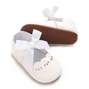 Vista detallada de zapatos de princesa para bebé blancos con lazo grande y suela blanda