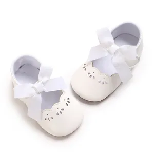 Vista detallada de zapatos de princesa blancos para bebé con lazo grande y calados