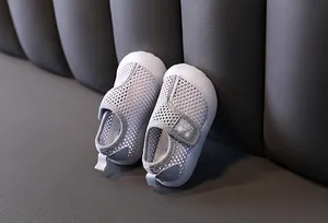 Nahaufnahme von grauen atmungsaktiven Mesh-Babyschuhen mit Klettverschluss auf Leder.