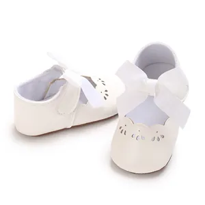 Primer plano de zapatos de princesa blancos para bebé con un lazo grande y bordes calados