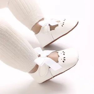 Detalle de zapatos blancos para bebé con lazo decorativo y diseño de borde festoneado