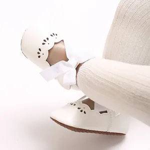 Detalle de zapatos de princesa para bebé blancos con lazo grande y suela blanda