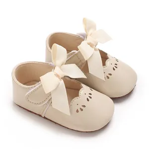 Primer plano de zapatos de princesa para bebé crema con lazos grandes y suela blanda
