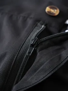 Makro-Detail des hochwertigen schwarzen Nylon-Reißverschlusses und Bernstein-Knopfes an Herrenshorts