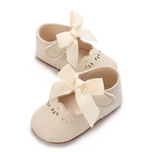 Primer plano de zapatos de princesa para bebé crema con lazo grande y calados finos