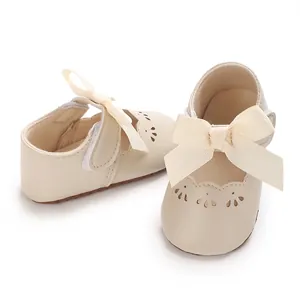 Primer plano de zapatos de princesa para bebé crema con lazos grandes y detalles.