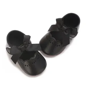 Detalle de zapatos de princesa negros para bebé con un lazo de cinta grande