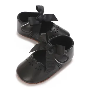Primer plano de zapatos de princesa negros para bebé con lazo y detalles calados