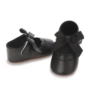 Primer plano de zapatos de princesa para bebé negros con lazo y troquelados en blanco