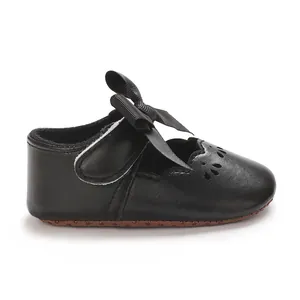 Detalle de zapatos de princesa para bebé niña en negro con lazo grande y festoneado