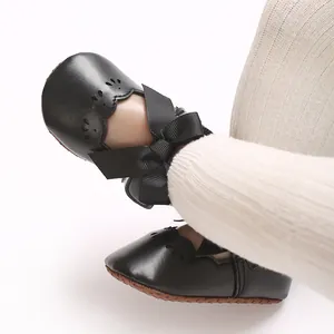 Detalle de zapatos negros para bebé niña con lazo grande y bordes festoneados elegantes