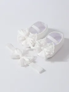 Close-up detail view of white lace bow baby shoes and matching elastic headband set.