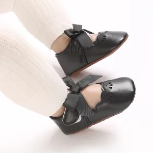 Detalle de zapatos de princesa para bebé negros con un lazo grande y bordes festoneados