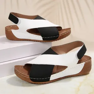 Detail of black and white color-block wedge sandals with velcro strap and platform sole.