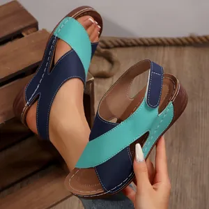 Primer plano de sandalias con cuña para mujer con tiras cruzadas azules y verdes y suela