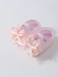 Close-up detail of pink baby girl princess shoes featuring a delicate lace bow design