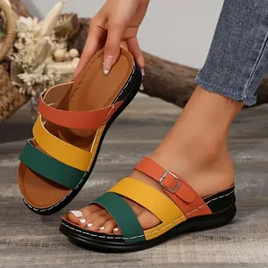 Detaillierte Ansicht bunter Keilsandalen mit drei Riemen und Schnallendetails am Fuß