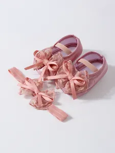 Detailed shot of pink baby girls pre-walker shoes with matching lace bow headband