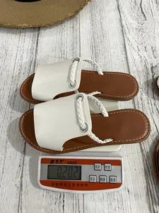 Detail shot of lightweight white braided flat sandals on a scale showing product weight