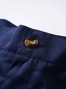 Detailansicht des hochwertigen Bundes und des braunen Knopfes an blauen Herrenshorts