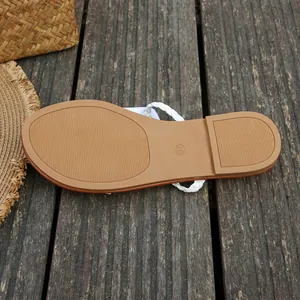 Detailed macro view of the non-slip tan sole and white braided strap of summer sandals