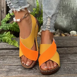 Close-up of yellow and orange patchwork wedge sandals with thick soles and peep-toes.