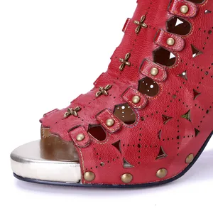 Primer plano de sandalia roja de cuero con tacón, diseño calado y tachuelas