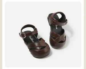 Detailed view of brown toddler girls sandals with buckle strap and cross design.