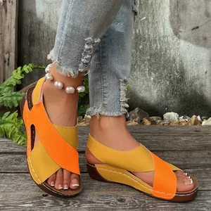 Detailed view of women's orange and yellow color block wedge sandals with white stitching