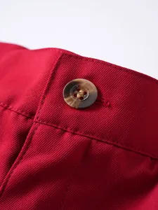 Nahaufnahme von rotem Köperstoff und Knopf mit Marmortextur an lässigen Herren-Shorts