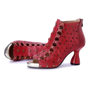 Detalle del patrón calado de cuero rojo y remaches vintage en botas de tacón alto