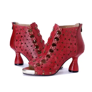 Detalle de botines de cuero rojo calados con remaches metálicos y tacón grueso exclusivo.