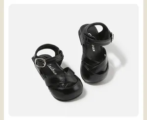 Detail view of black toddler girl sandals featuring criss-cross straps and silver buckles.