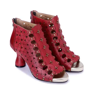 Detalle de botines rojos de cuero calado con tachuelas y tacón alto de estilo retro.