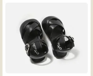 Close-up view of black baby girl sandals featuring stylish criss-cross strap design