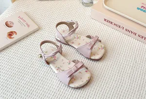 Pink girl's flat sandals with elegant bow and floral insole on a white background.