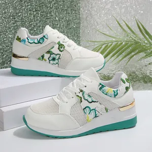 Πλαϊνή όψη λευκών sneakers με πλατφόρμα, δίχτυ και πράσινο κέντημα με λουλούδια.