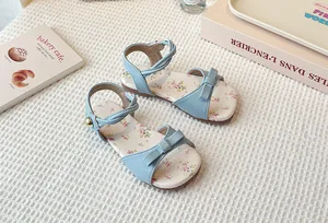 Detailed view of light blue children's flat sandals with floral print and bow