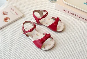 Close-up shot of red girls' sandals featuring bow details and floral pattern insoles