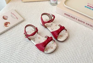 Close-up of red girls' sandals with floral insoles and cute bow details in a lifestyle setting