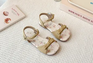 Close-up of girls' floral flat sandals with beige bow and velcro ankle strap