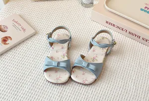Close-up detail of light blue girls flat sandals featuring floral insole and cute bow decoration.