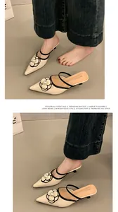 Gros plan de mules élégantes à petits talons beiges avec détail de fleur de perle