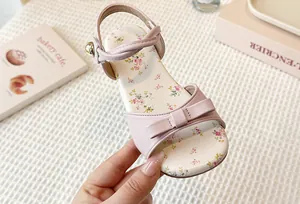 Detailed close-up of girls' pink princess sandal with bow and floral printed insole