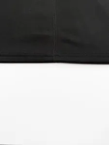 Macro detail of black ribbed knit fabric showing high-quality stitching and seam work.