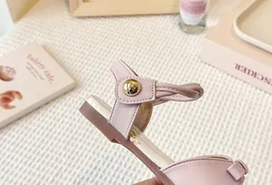 Detailed close-up view of a pink girl's floral flat sandal strap with a gold buckle