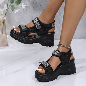 Gros plan sur des sandales compensées noires avec brides en strass et velcro